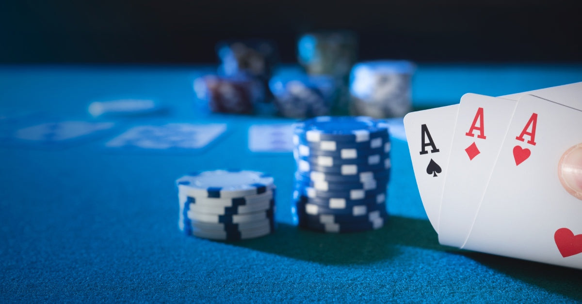 A point-of-view of a person playing cards at a professional table with two stacks of gambling chips and three aces.