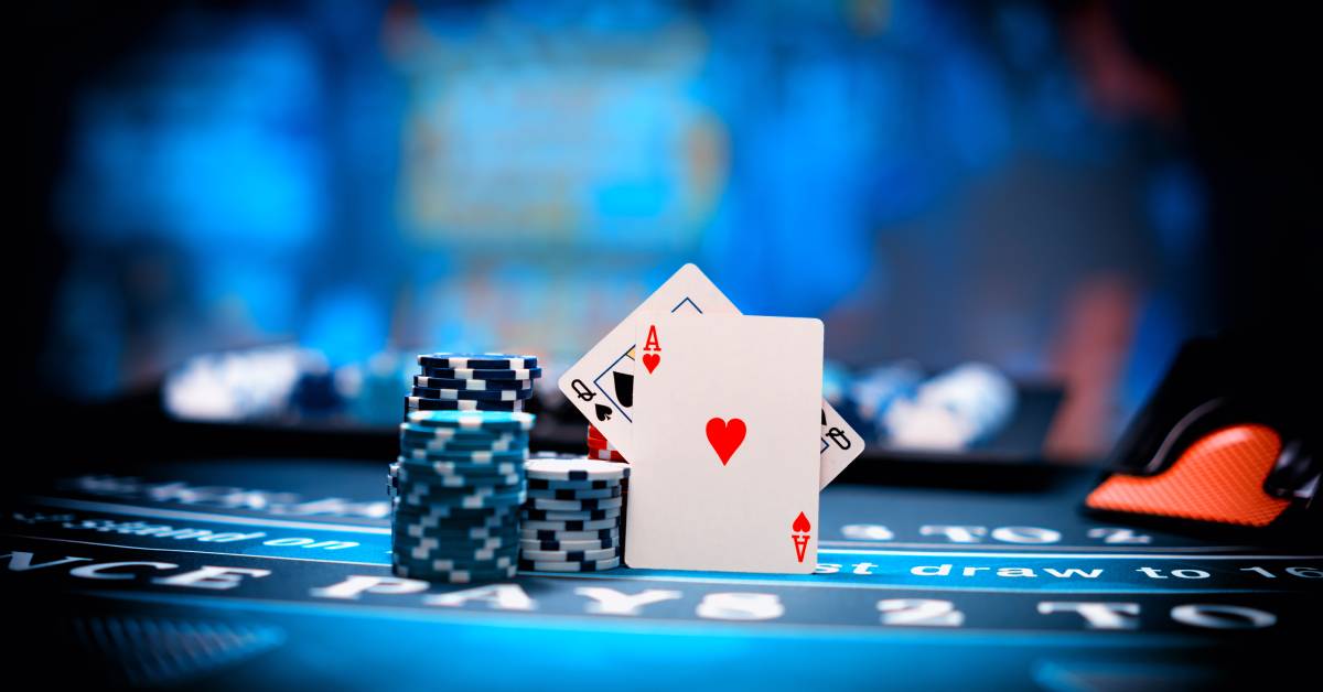 A vertical display of the queen of spades and ace of hearts against a stack of gambling chips on a blackjack table.