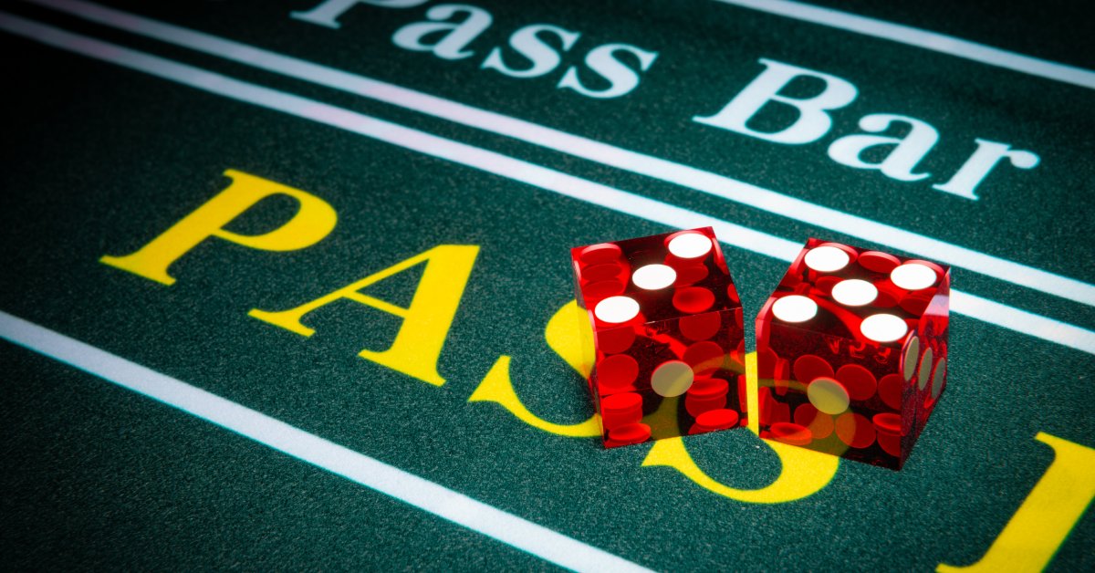 A pair of clear red dice placed on the felt of a craps table with the "pass line" and "don't pass" bar underneath.